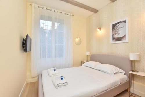 une chambre avec un lit blanc et une fenêtre dans l'établissement Cosy apartment - Buttes aux Cailles, à Paris