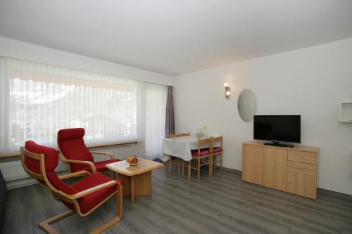 a living room with chairs and a tv and a table at Apartments Haus Quelle in Leukerbad