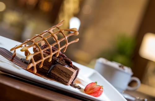 a piece of chocolate cake on a plate with a strawberry at Millennium Kurdistan Hotel & Spa in As Sulaymānīyah