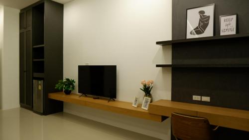 a living room with a television on a wooden shelf at The Midst by The M - Nakhon Nayok TMD4 in Ban Som Phung Haeng (1)