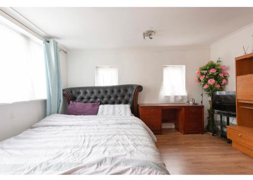 a bedroom with a large bed and a desk and window at Quite studio in Hendon
