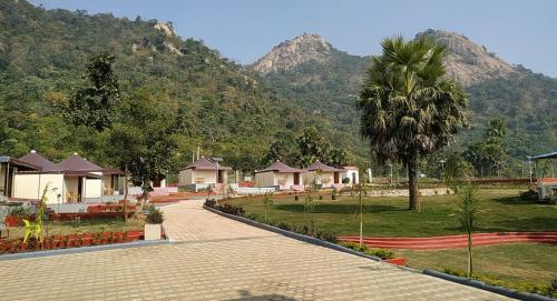 a resort with a palm tree and a mountain at Matha Forest Resort in Purulia
