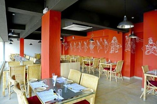 Hotel Siri Inn في حيدر أباد: غرفة طعام بجدران حمراء وطاولات وكراسي