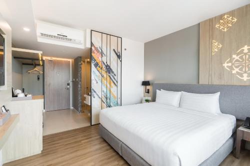 a bedroom with a large white bed and a kitchen at Hotel Amber Pattaya in Pattaya Central