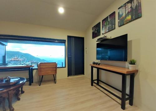 a living room with a desk with a television and a table at Dosun B&B in Jiufen