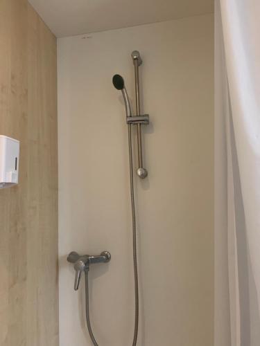 a shower in a bathroom next to a wall at Hotel Eco Blois in Vineuil