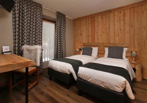 a hotel room with two beds and a desk at Assietta in Sauze dʼOulx