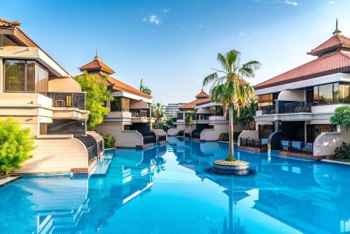 a resort pool with a palm tree in the middle at Luxe Getaways Royal Amwaj Palm Jumeirah Resort Apartment Holiday Home in Dubai