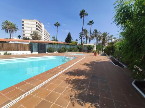 an empty swimming pool with palm trees and a building at 2 bedroom bungalow next Yumbo Center. free parking in Playa del Ingles