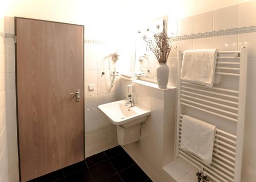 W białej łazience znajduje się umywalka i lustro. w obiekcie Hotel Flämischer Hof w Kilonii