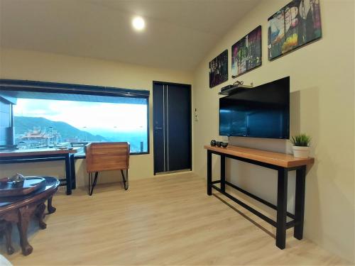 a living room with a desk and a large window at Dosun B&B in Jiufen