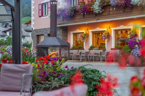 a courtyard with tables and flowers in front of a building at Hotel La Serenella in Moena