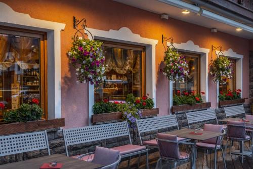 a restaurant with tables and chairs and flowers at Hotel La Serenella in Moena