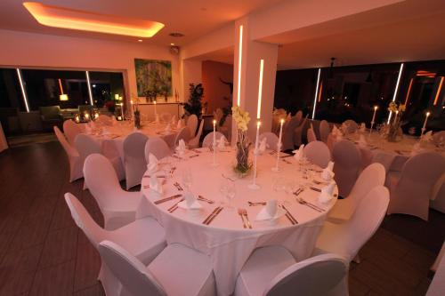 パッテンゼンにあるzeitlos Hotel und Restaurant am Fuchsbachの白いテーブルと白い椅子が備わる宴会場
