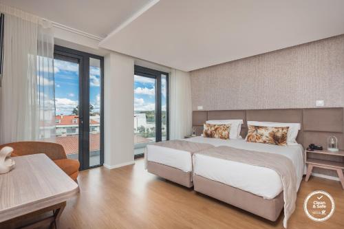 ein Schlafzimmer mit einem großen Bett und einem großen Fenster in der Unterkunft Essence Inn Marianos Hotel in Fátima