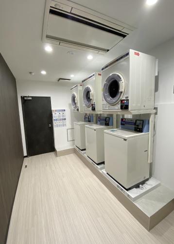 a laundry room with three washers and dryers on display at Santiago Hotel in Hiroshima