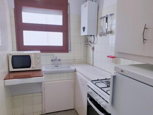 eine kleine weiße Küche mit einer Spüle und einer Mikrowelle in der Unterkunft El mariner, apartamento de dos habitaciones, U4 in Port de la Selva