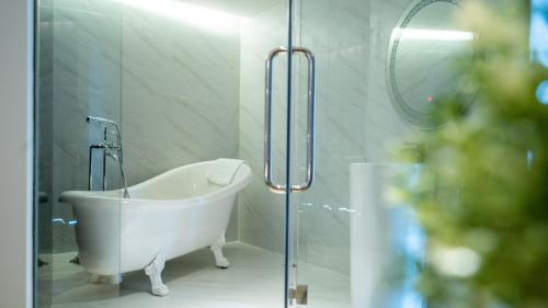 a white bath tub in a bathroom with a glass door at Pannarai Hotel Bangkok in Bangkok