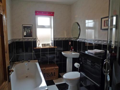 a bathroom with a tub and a toilet and a sink at Little Irish Cottage in Carrick