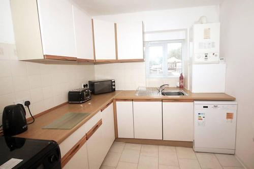 a small kitchen with white cabinets and a sink at No 28B St Benedict in Glastonbury