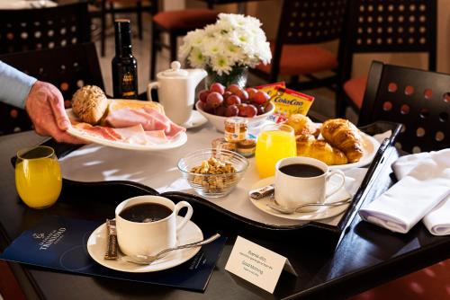 Una mesa con alimentos para el desayuno y tazas de café. en La Casa de la Trinidad, en Granada