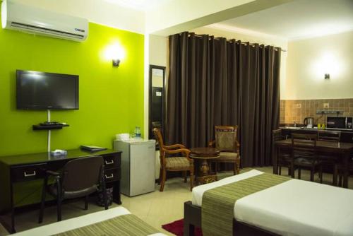 a hotel room with two beds and a desk with a television at Hotel Sapphire in Dar es Salaam