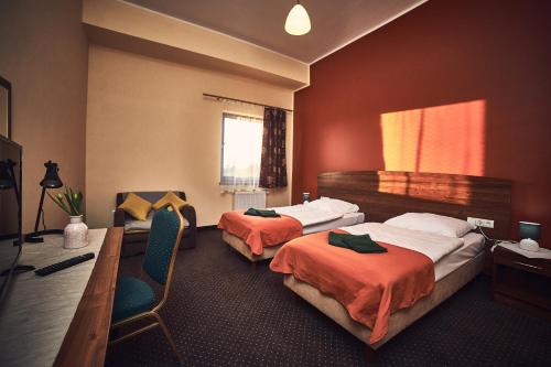 a hotel room with two beds and a desk at Hotel AB in Tychy