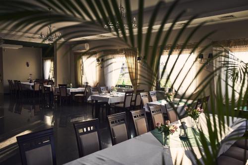 a dining room with tables and chairs and plants at Hotel AB in Tychy