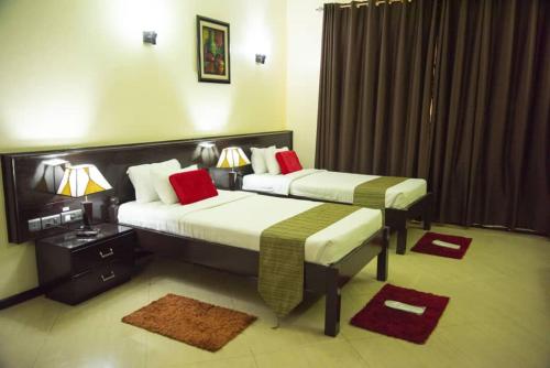 two beds in a hotel room with red pillows at Hotel Sapphire in Dar es Salaam