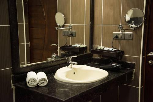 a bathroom with a sink and a mirror and towels at Hotel Sapphire in Dar es Salaam