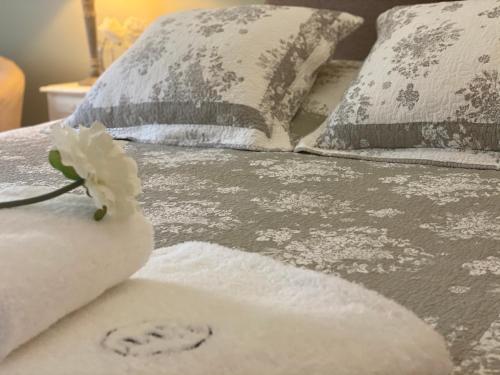 ein Bett mit Kissen und einer weißen Blume darauf in der Unterkunft Le Moulin de Rudelle in Muret