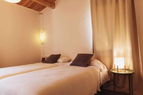 a bedroom with two beds and a table with a lamp at Casa Diana C in Girona