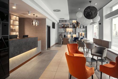 a restaurant with orange chairs and tables and a bar at Astoria Hotel in Prague
