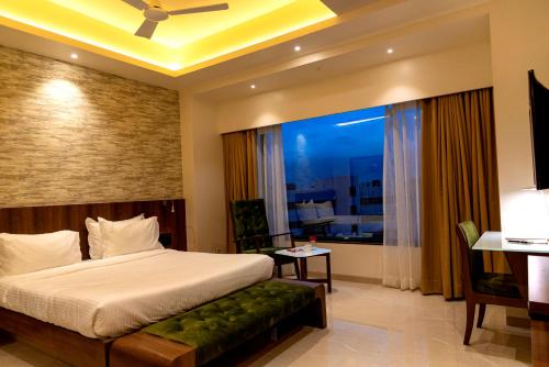 a bedroom with a bed and a desk and a window at Hotel Pratham in Solapur