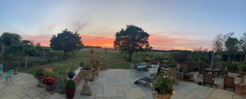 a garden with potted plants and a sunset in the background at Newmans Lodge in Lavenham