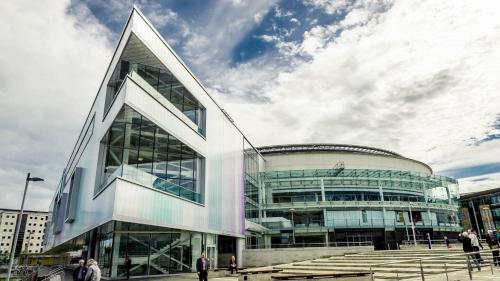a large glass building with people walking around it at Holiday Inn Express Belfast City by IHG in Belfast