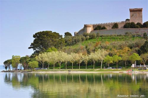 un castello in cima a una collina vicino a un corpo d'acqua di Hotel La Torre a Castiglione del Lago