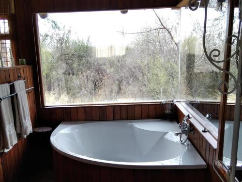 a bath tub in a bathroom with a window at Hanlin Lodge in Modimolle