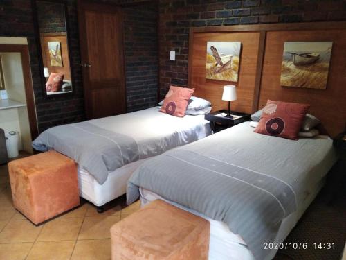 a hotel room with two beds and two tables at Hanlin Lodge in Modimolle