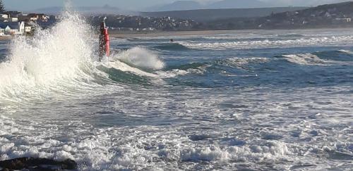 a wave in the ocean with a red object in the water at Lieflappie❤ in Stilbaai