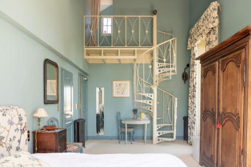 a bedroom with blue walls and a spiral staircase at Chateau de Varenne in Sauveterre