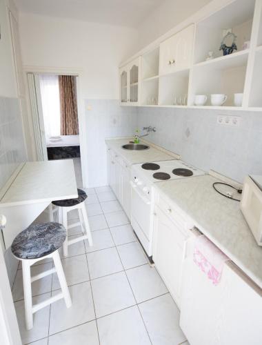 a white kitchen with a stove and a sink at Panzió LEMBERG in Hajdúszoboszló
