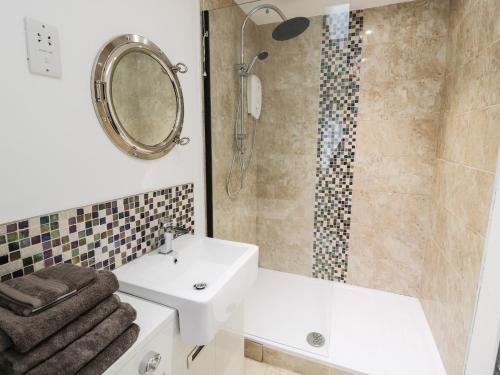 a bathroom with a sink and a shower with a mirror at Swale Cottage in Chathill