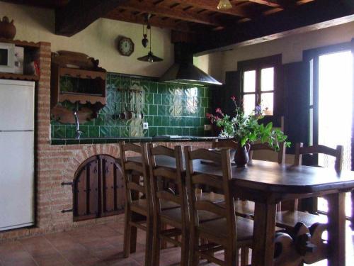 una cocina con una mesa de madera y algunos azulejos verdes en Casas rurales Caño Chico y La Fuente, en Villanueva del Conde