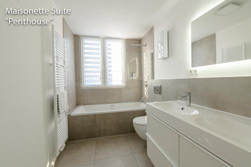 a white bathroom with a sink and a tub and a toilet at Downtown Apartments Bilk in Düsseldorf