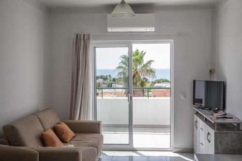 a living room with a couch and a view of the ocean at Debimar Apartamentos in Albufeira