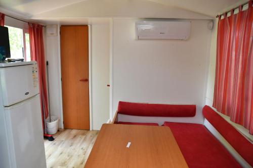 um pequeno quarto com uma mesa de madeira e um frigorífico em Balatontourist Berény Naturist Camping em Balatonberény