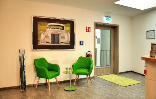 a waiting room with two green chairs and a car on the wall at Motel am Fürfelder Schloss in Bad Rappenau