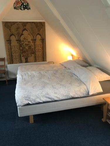 a bedroom with a bed with white sheets on it at B&B De Duinhoek in Beverwijk