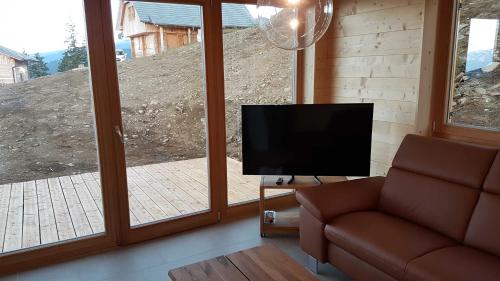 a living room with a couch and a flat screen tv at Ferienhaus Murmeltier am Klippitztörl in Klippitztorl